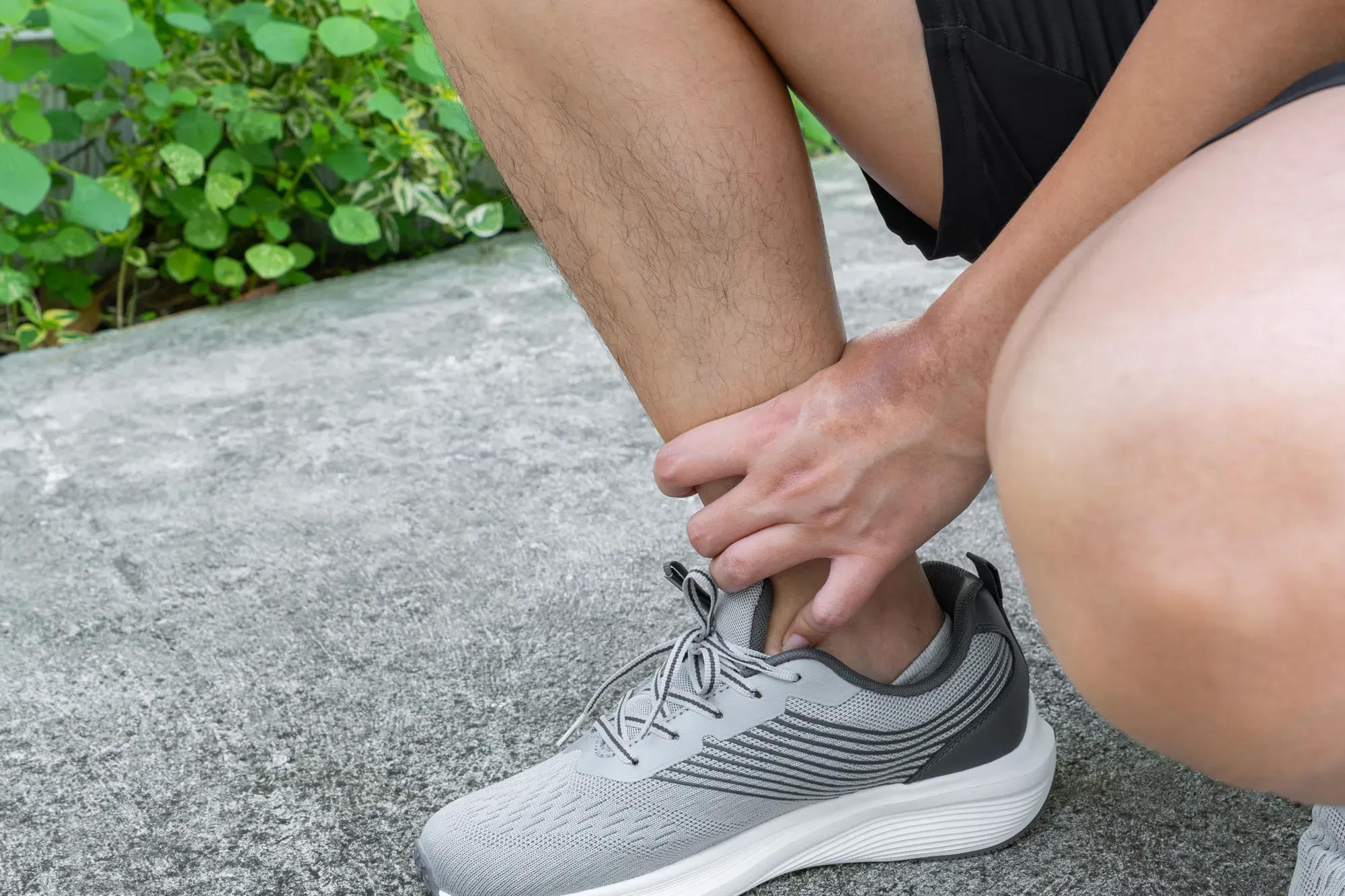 Close-up of a man feeling his ankle while experiencing chronic instability.