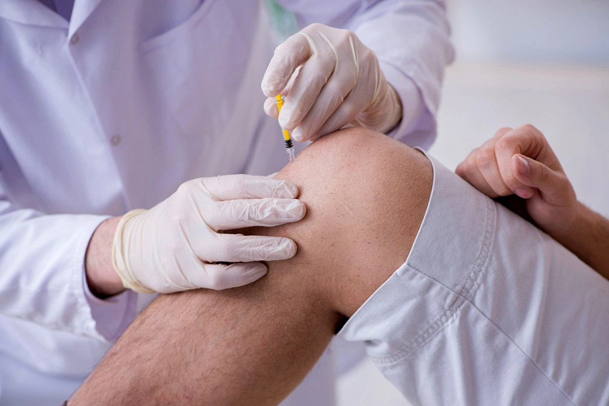 A man receiving treatment from a doctor for his knee pain