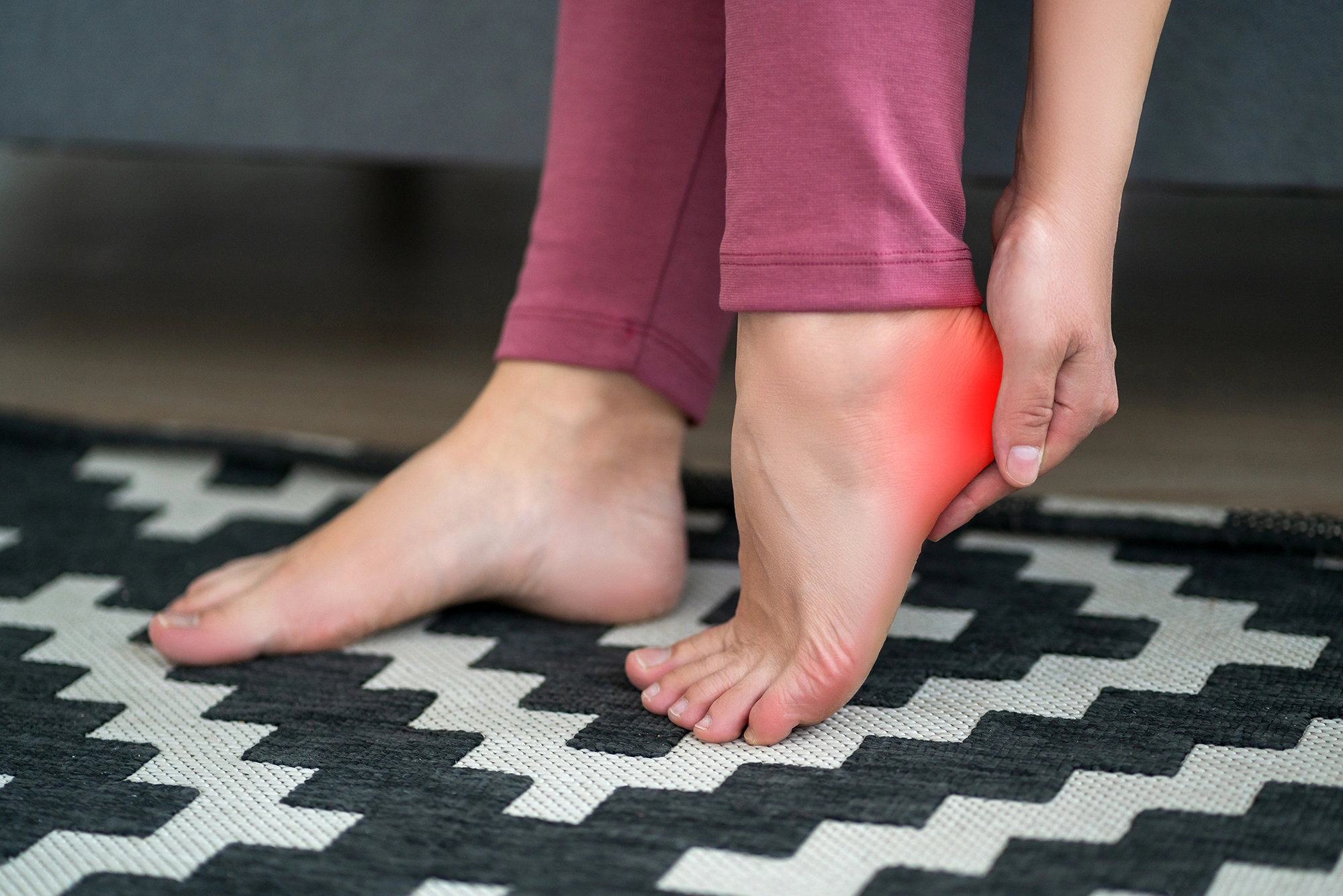 Person touching the heel to indicate pain on the underside of the foot.