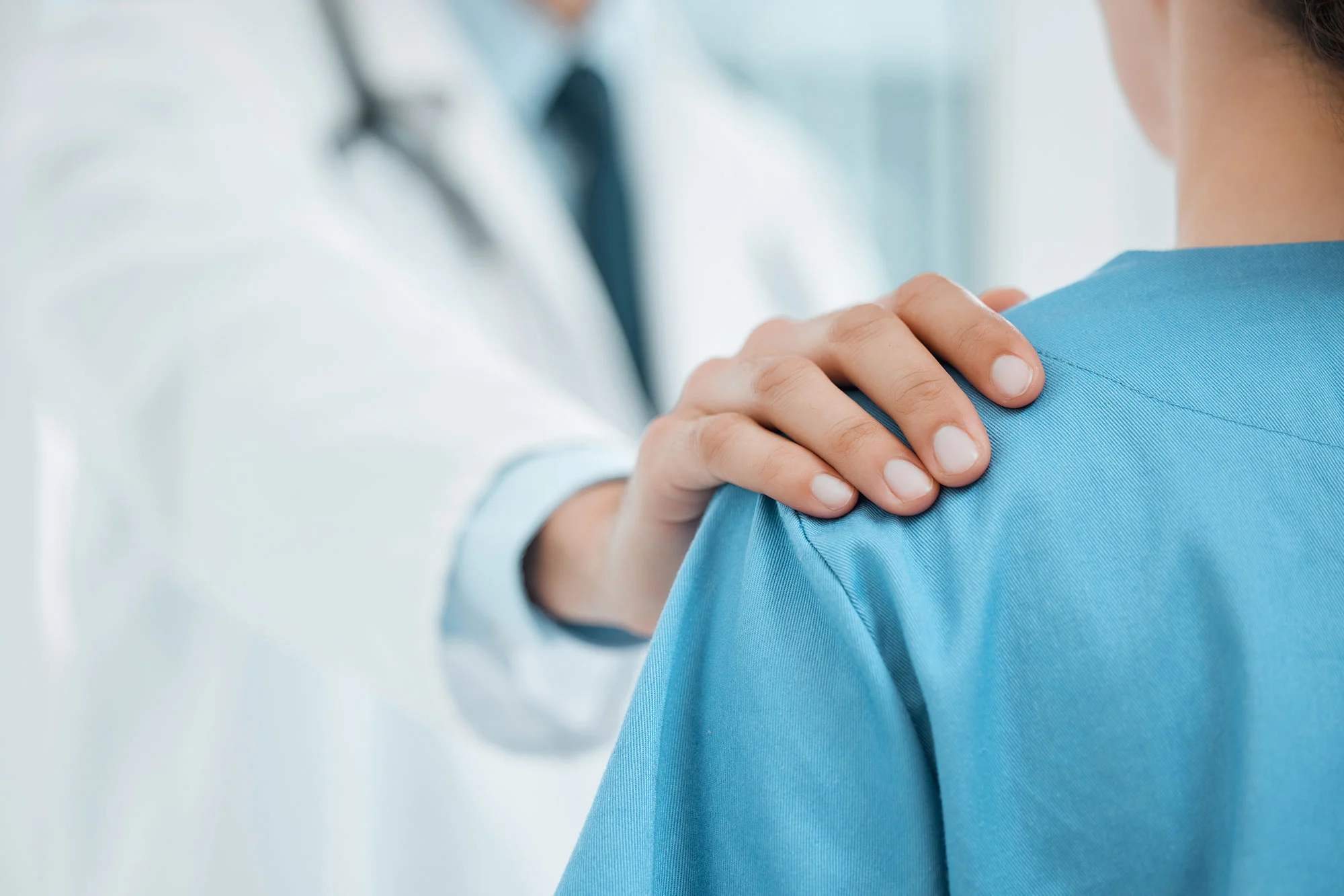 A doctor placing his hand on a patient's shoulder as a sign of reassurance